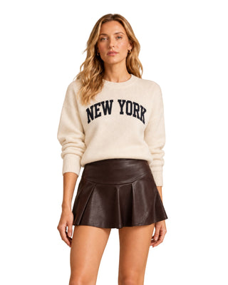 New York Letter Sweater Top in cream with navy lettering, front view with brown leather mini skirt