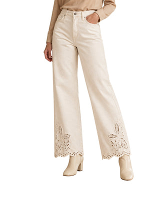 Lili High Waist Embroidered Pants in white, front view on a model with eyelet embroidery at the hem and ivory boots