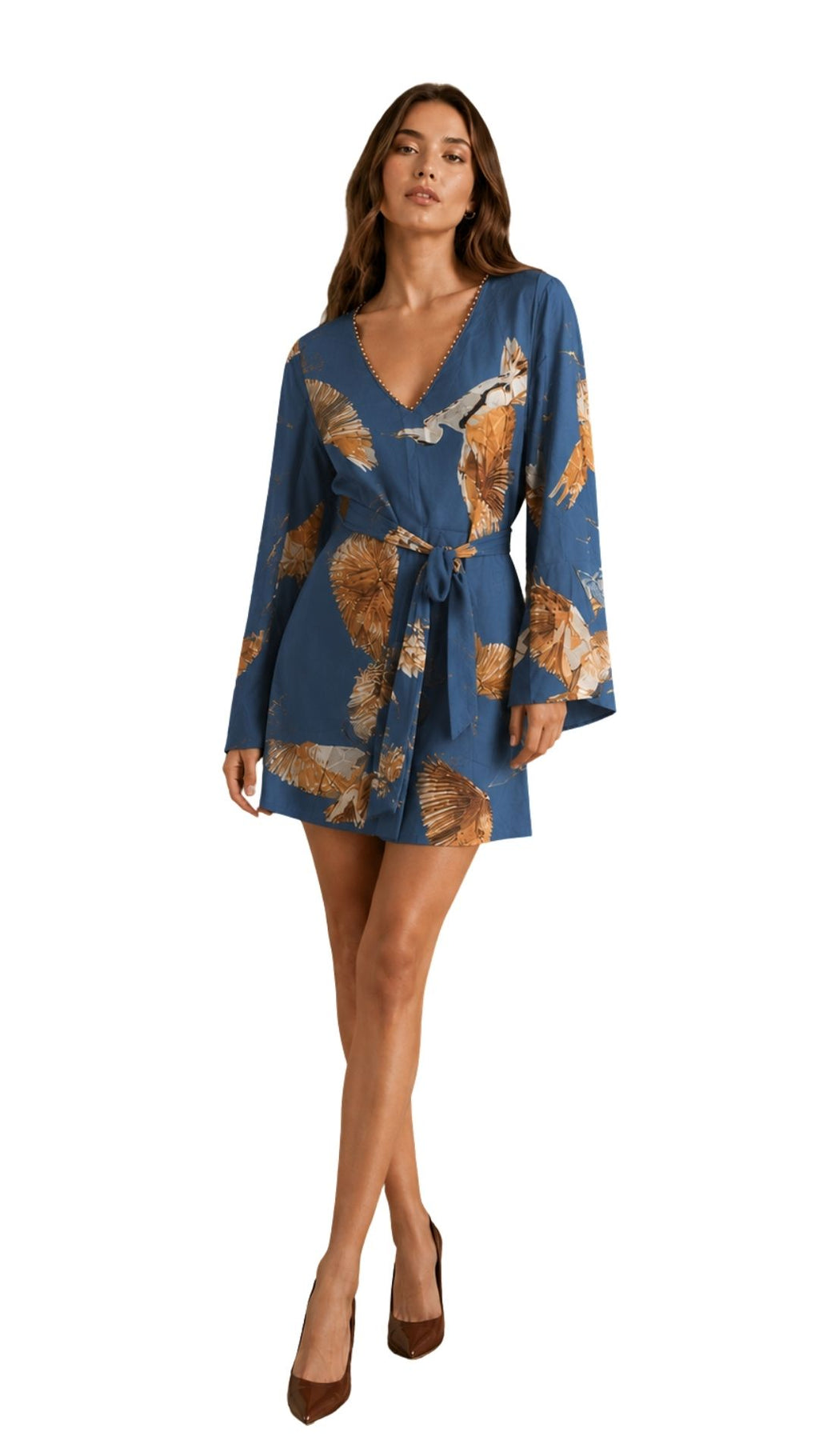 A woman modeling a blue long-sleeve wrap dress with a brown and beige abstract floral pattern, paired with brown pointed-toe heels, against a plain white background.
